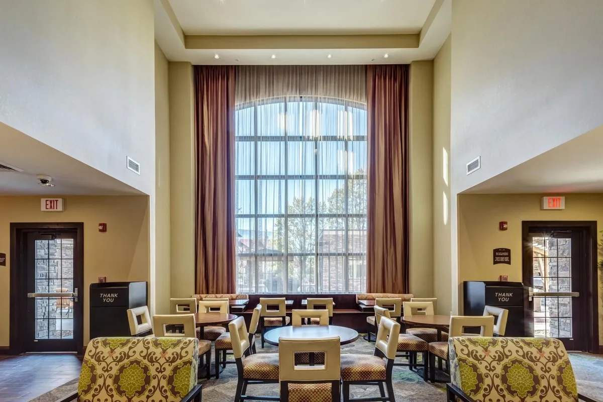 A contemporary lounge area bathed in natural light from large windows, featuring comfortable seating and modern decor. The space is ideal for relaxing, casual meetings, or socializing, capturing the blend of private comfort and communal usability.