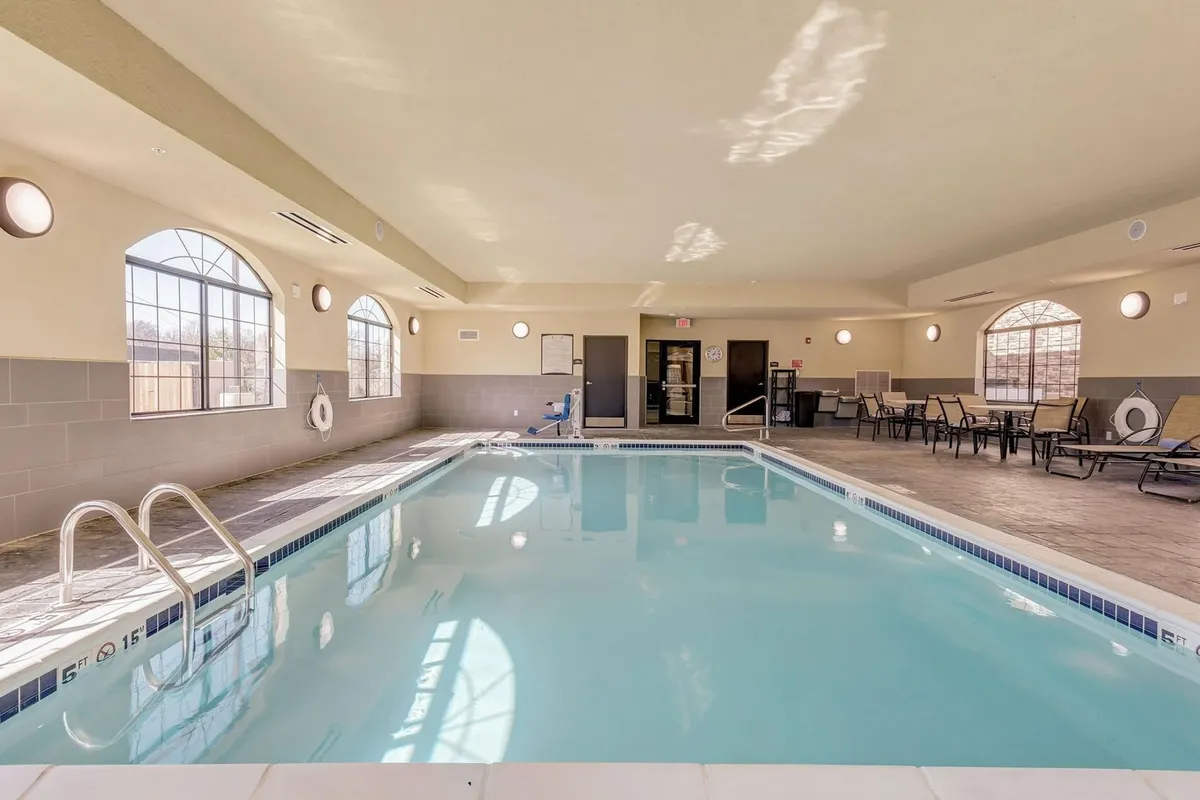 The hotel’s indoor swimming pool area features a sparkling pool, large windows that bring in natural light, and a comfortable seating area. The atmosphere suggests fun family time and relaxation after a busy day.