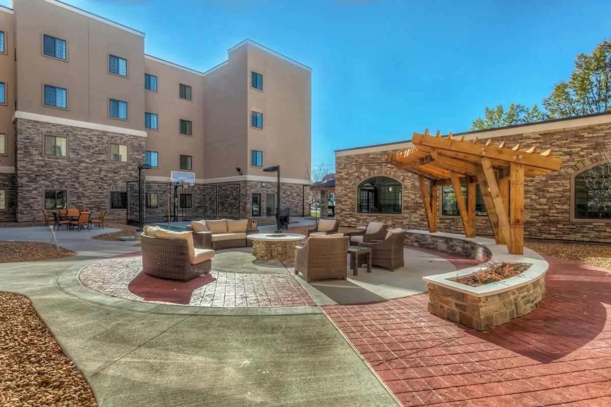 An inviting outdoor seating area under a pergola, complete with a cozy fire pit and pathway, surrounded by greenery. The space encourages social gatherings and moments of relaxation after a day of exploring.